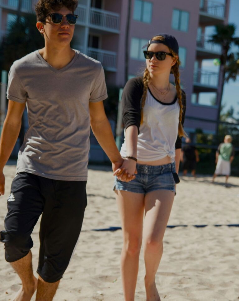 Couple walking closely on sand, reconnecting emotionally and physically during early postnatal Newborn Adjustments.