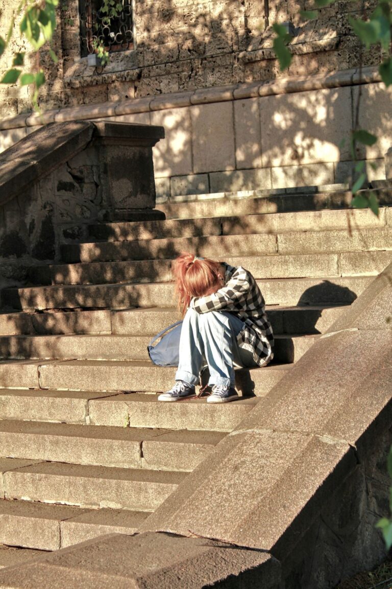 Person sitting alone, showing emotional distress and quiet reflection Understanding Self Harm Causes.