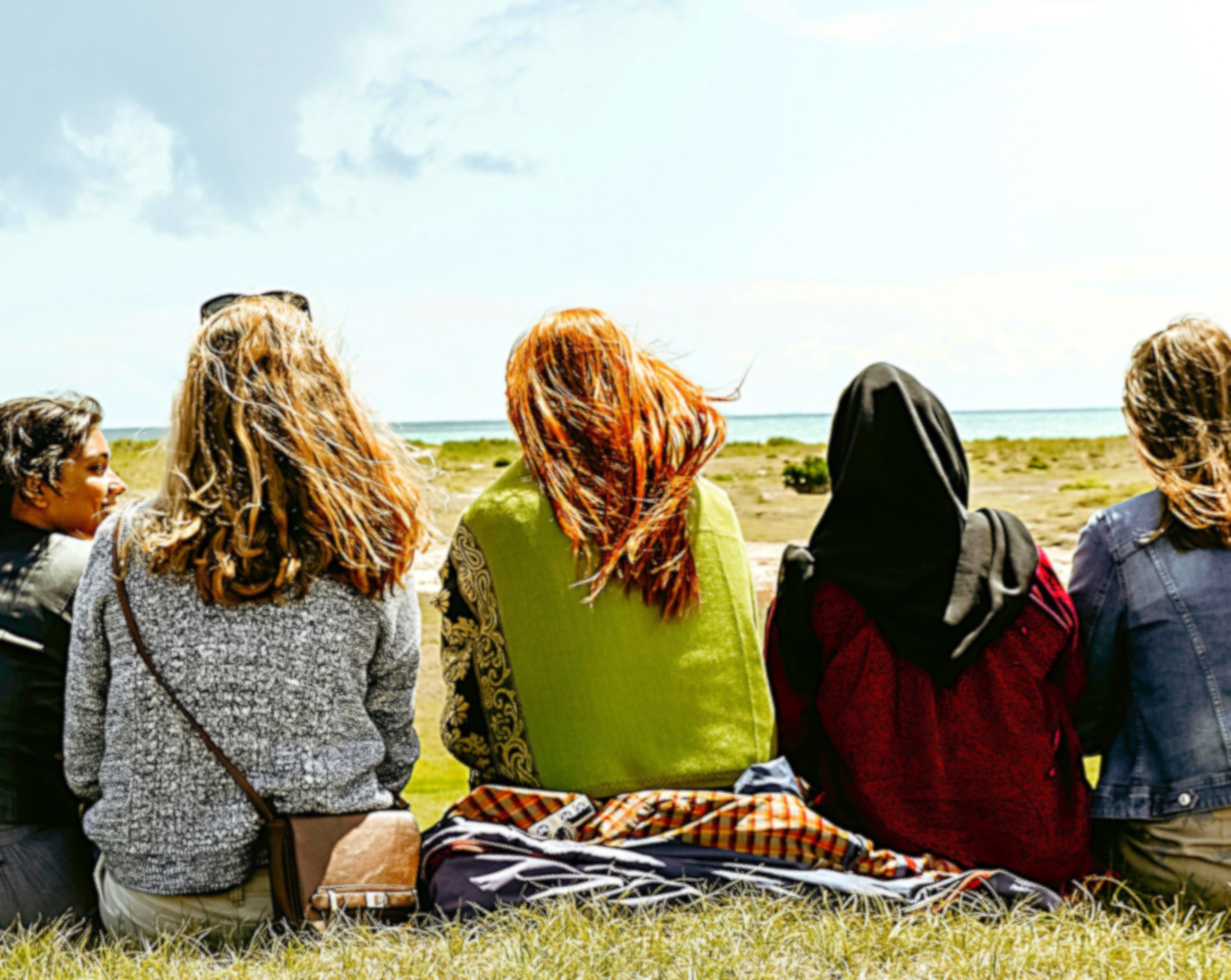 Reflective group sitting outdoors near the coast, engaging in mental health support or mindfulness activities amidst nature.