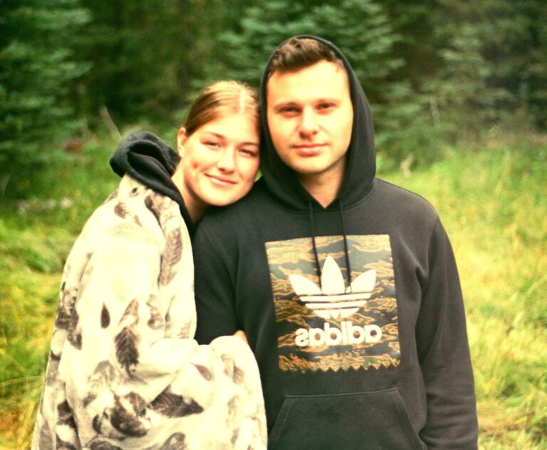 Calm young couple embracing outdoors in a forest setting, symbolising emotional connection and support for mental health.