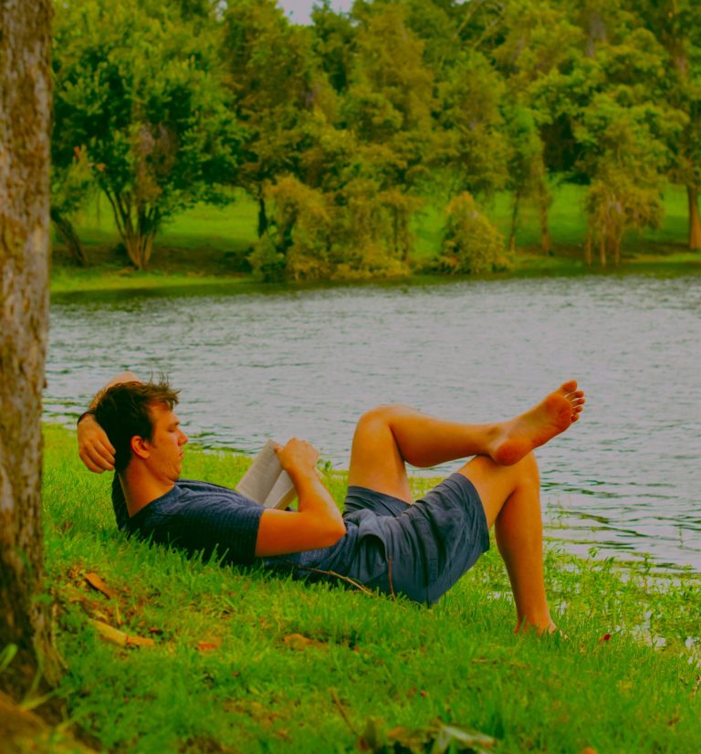 Man reading by the water, relaxing through hobbies and Finding Daily Motivation for growth and confidence.