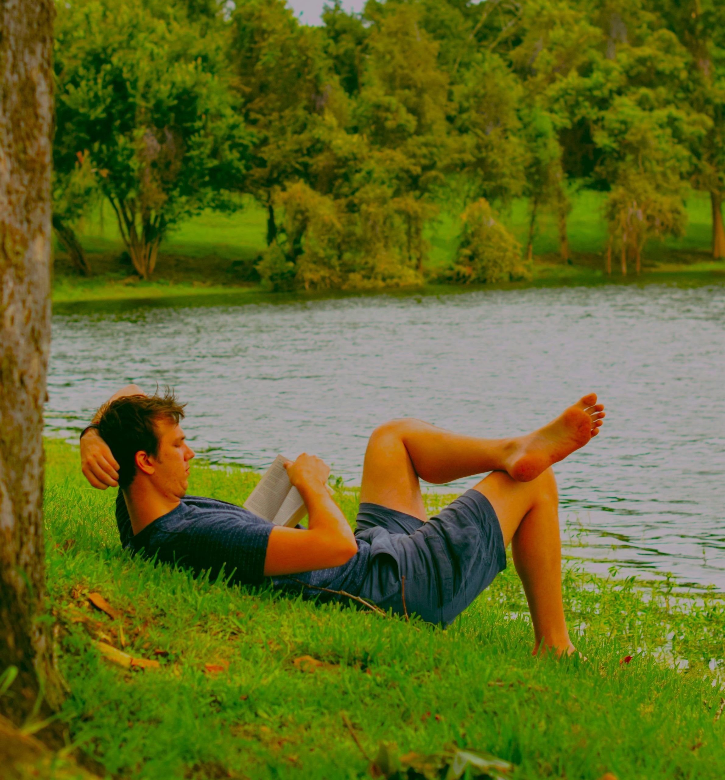 Man reading by the water, relaxing through hobbies and Finding Daily Motivation for growth and confidence.