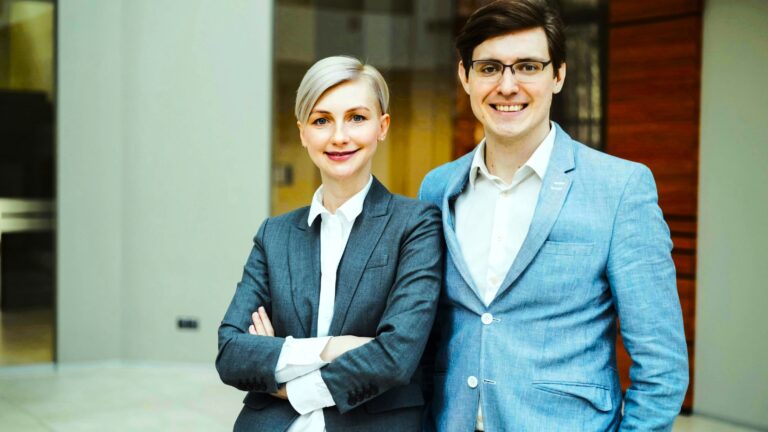 Professional couple collaborating confidently in an office, showing challenges and success of Relationships In Workplaces.