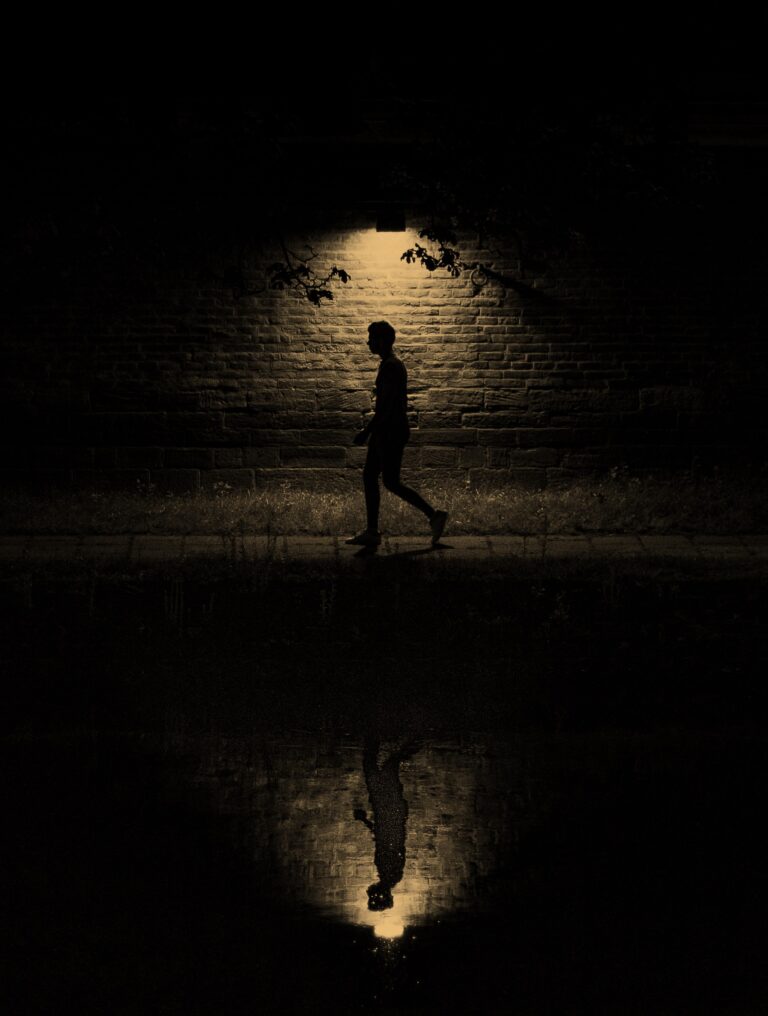 A person walks alone in darkness, reflecting trauma’s unseen toll and the Psychological Reactions it creates within.