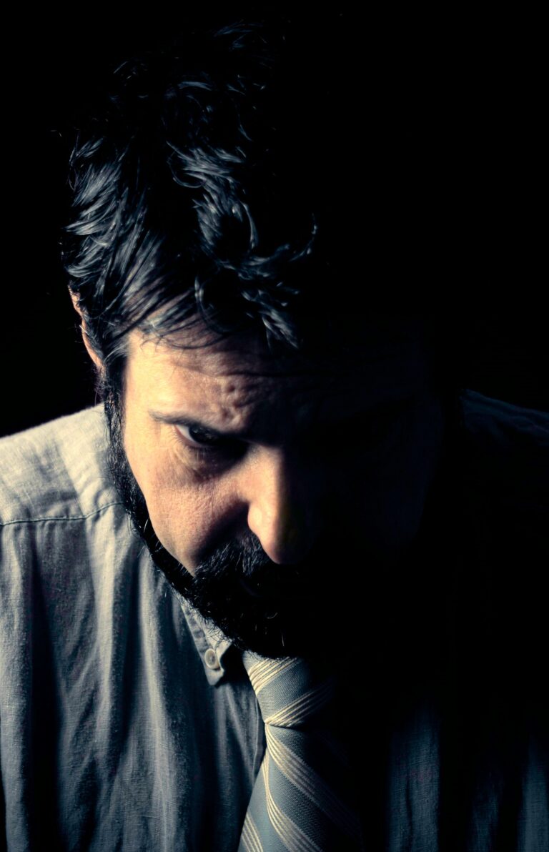 A grieving man sits in darkness, slowly Understanding Grief After Loss as a part of inevitable life.