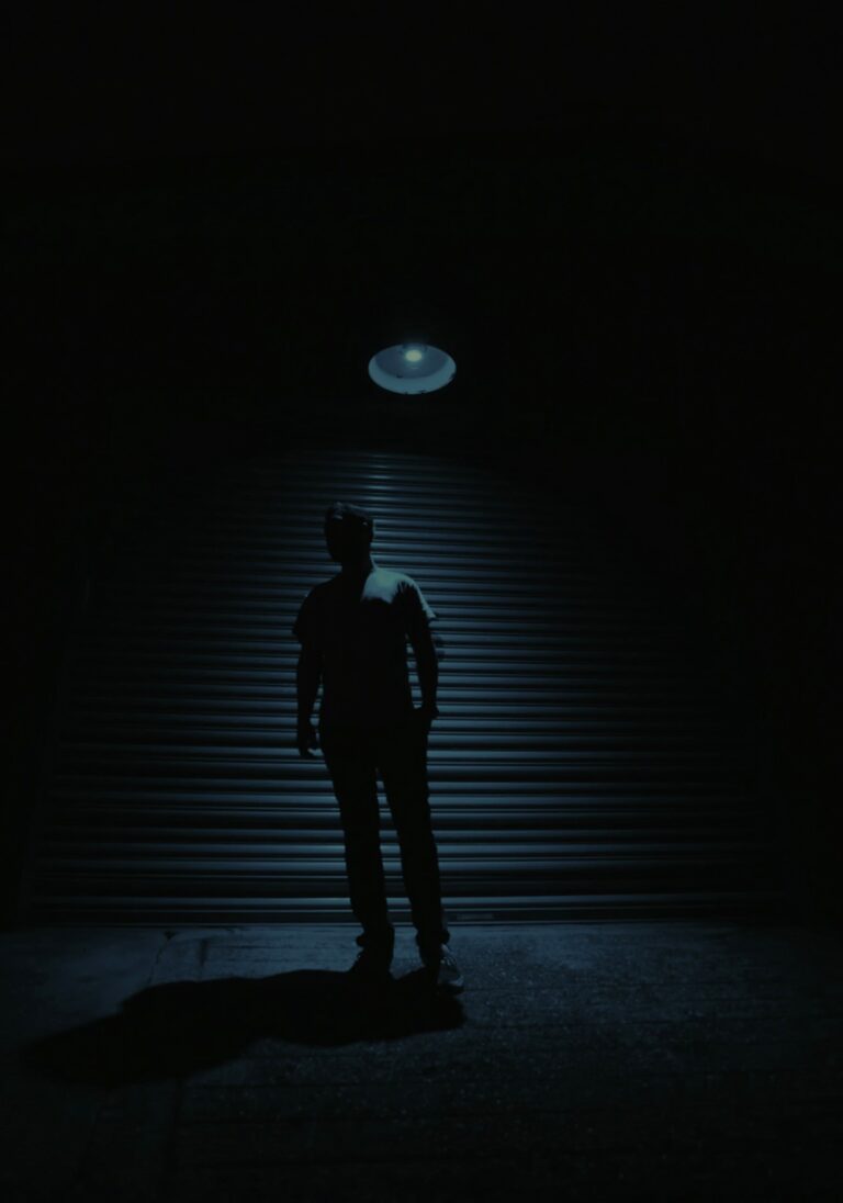 Person stands alone under dim light symbolising isolation caused by self-despair and the Common Roots Of Shame.