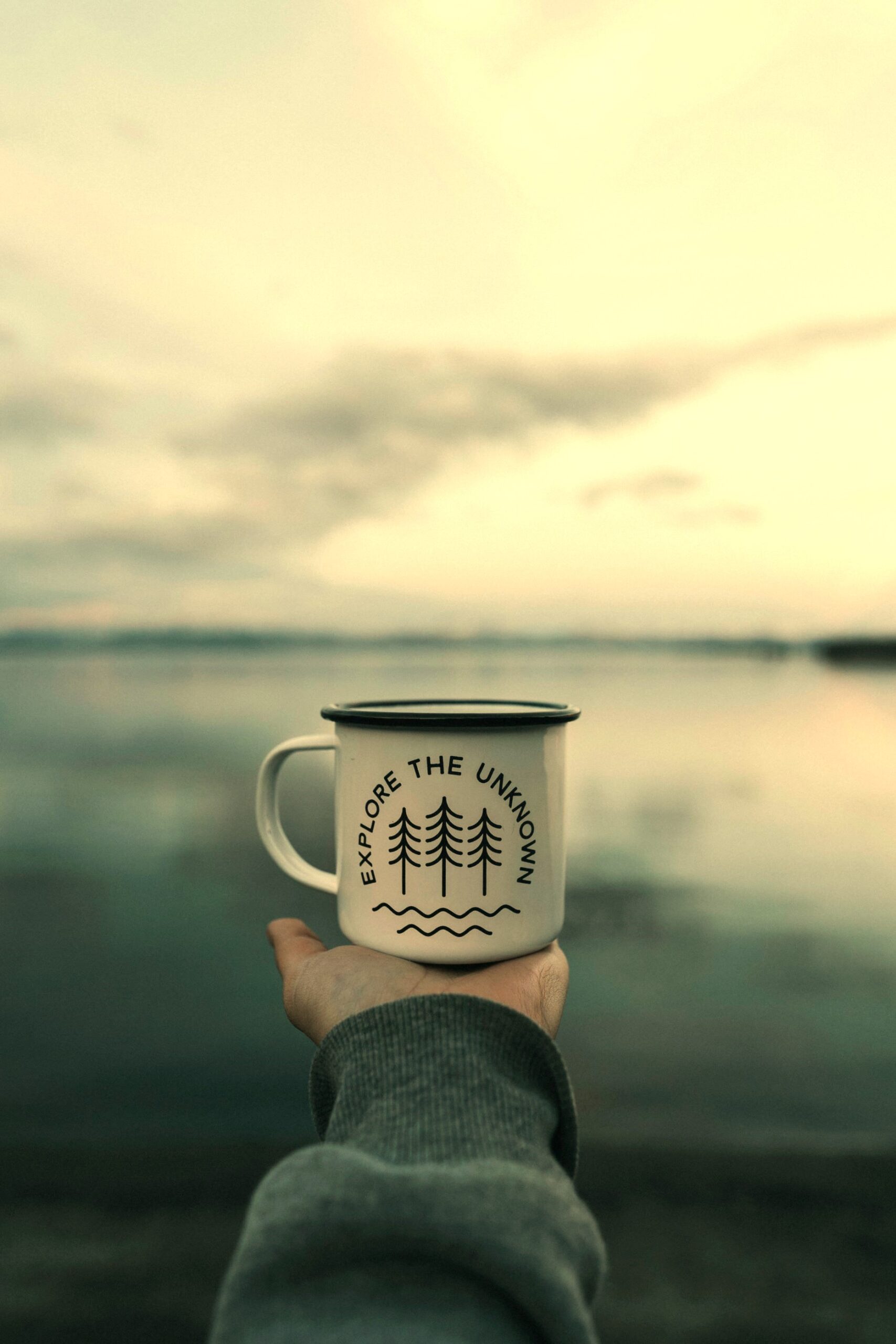 Hand holds mug marked 'Explore the Unknown', symbolising authentic self-growth through setting Realistic Goals.