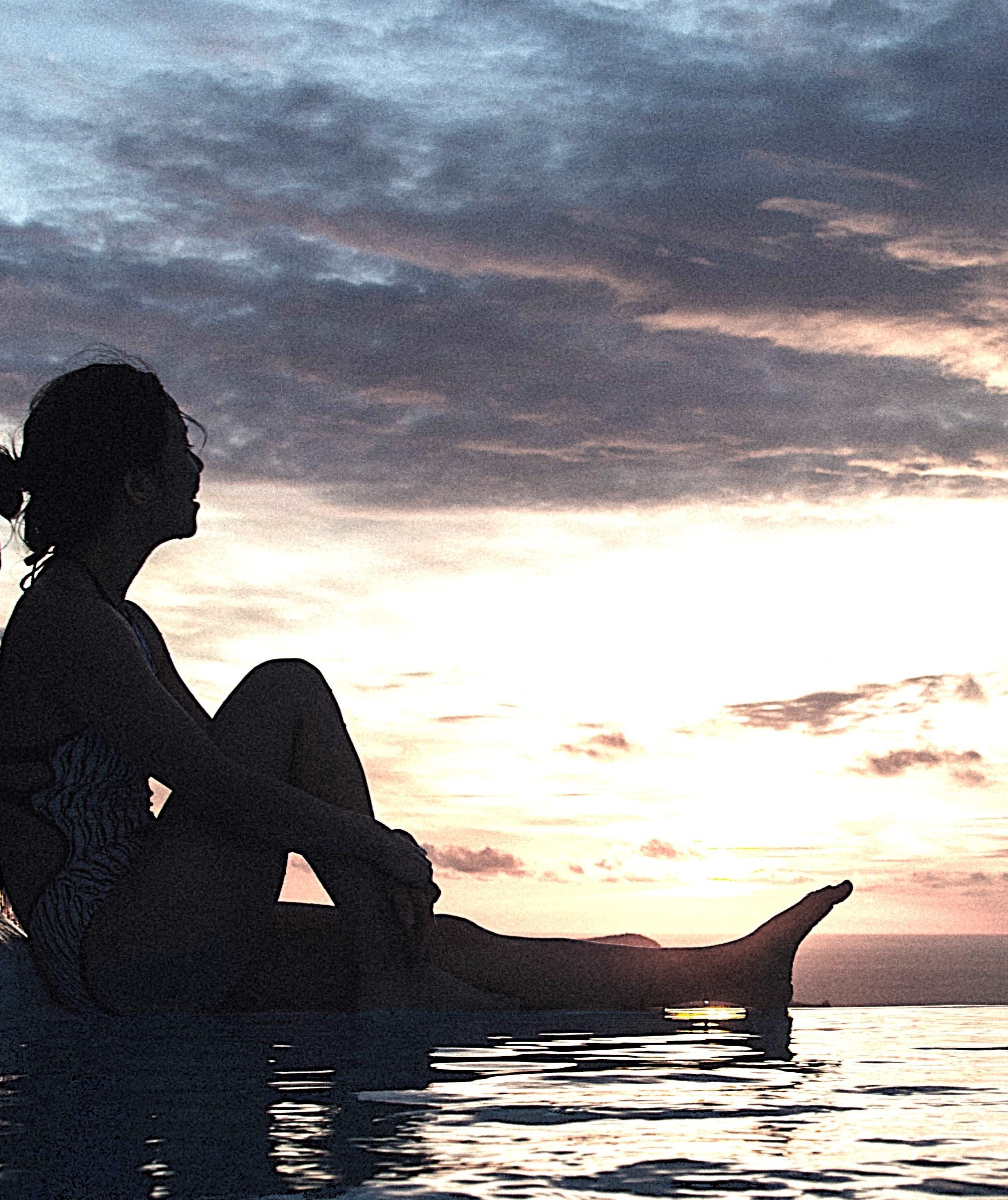 Silhouette of a person by water at sunset, Exploring Emotional Loneliness through self-reflection and personal growth.