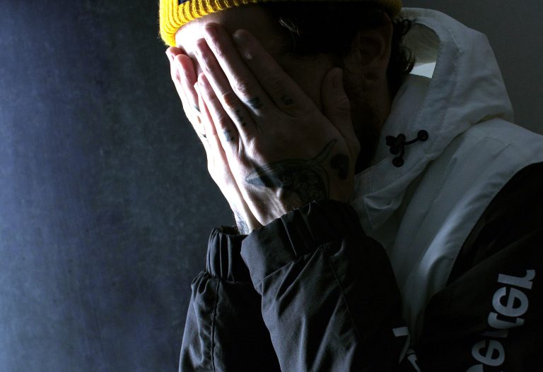 Person covering face with hands, showing distress and mental health struggles, highlighting Recognising Warning Signs importance.