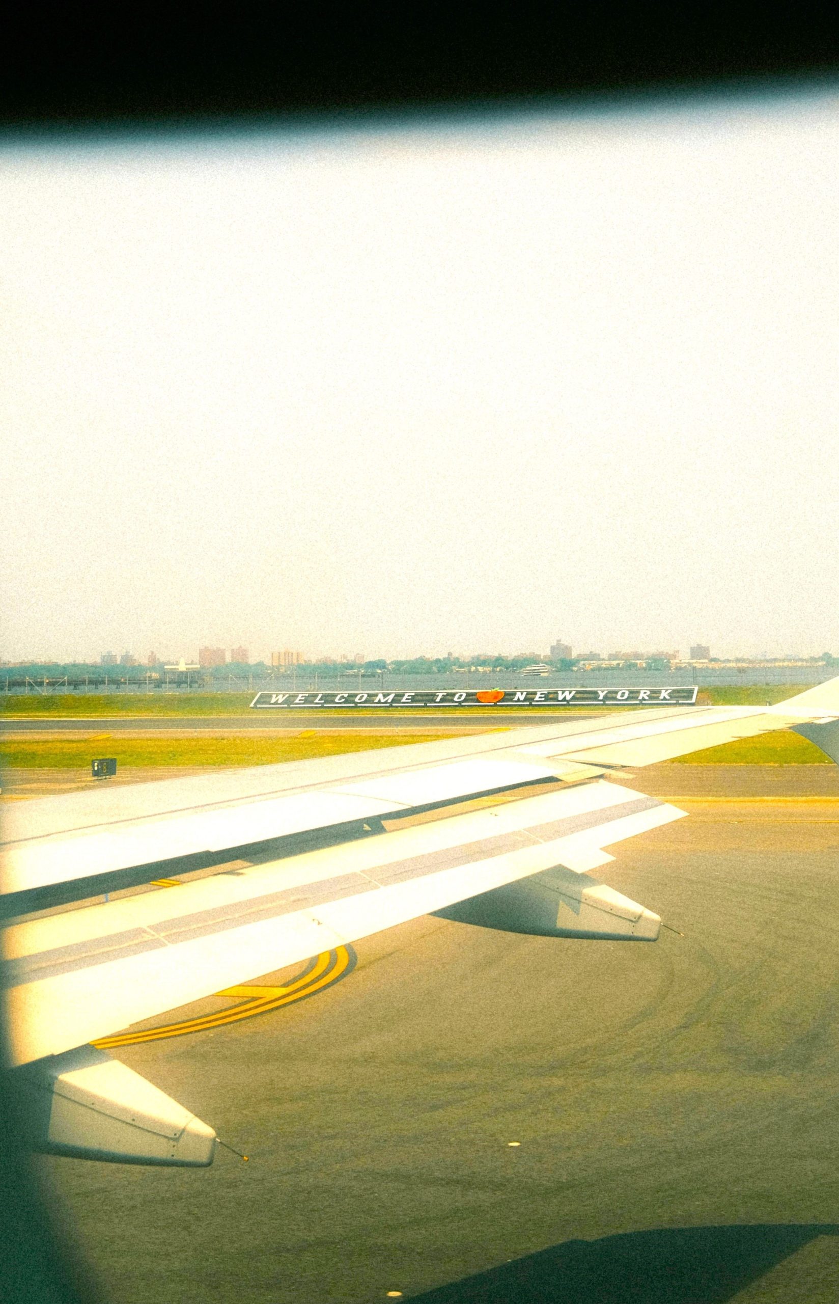 Airplane wing above runway with welcome sign, symbolising travel, change, and courage with Zero Resistance Mindset.