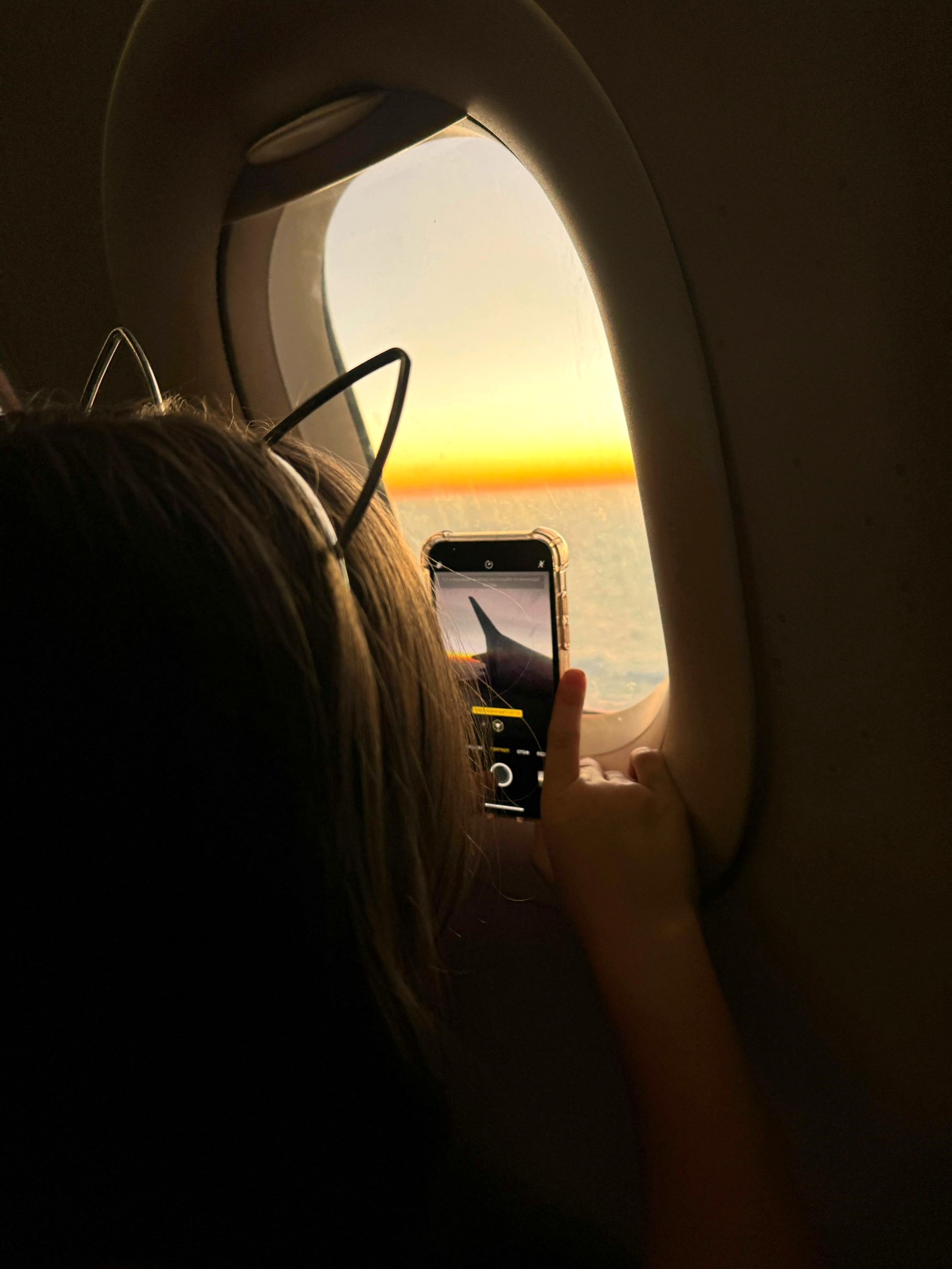 Child looking out airplane window, during family travel, learning routines and behavior tips and tricks with a Children Flight Preparation Guide.
