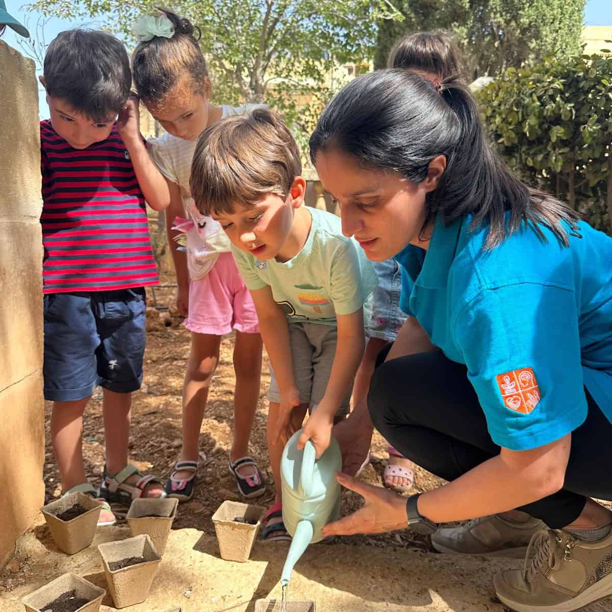 Children engaging in outdoor activity with adult supervision, learning about nature and responsibility, promoting emotional development and social interaction.