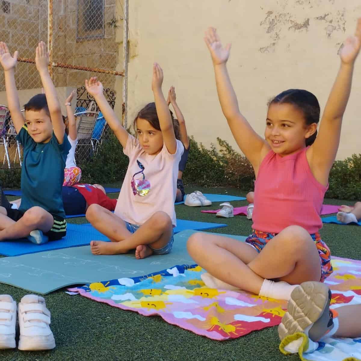 Children participating in outdoor yoga session, promoting mental wellness and relaxation in a calming environment. Practicing mindfulness and physical activity supports emotional development in children.