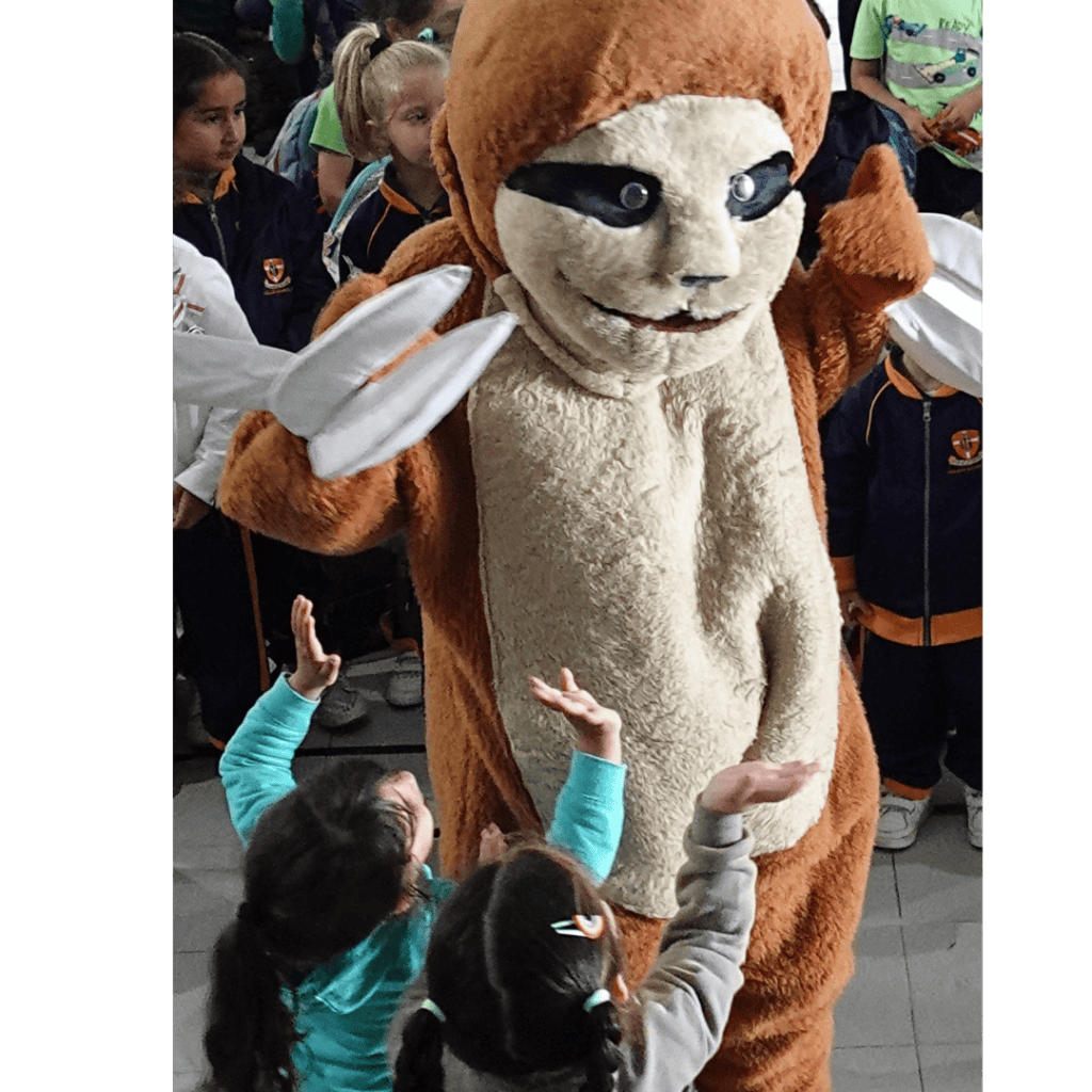 Friendly mascot costume interaction with young children at event.