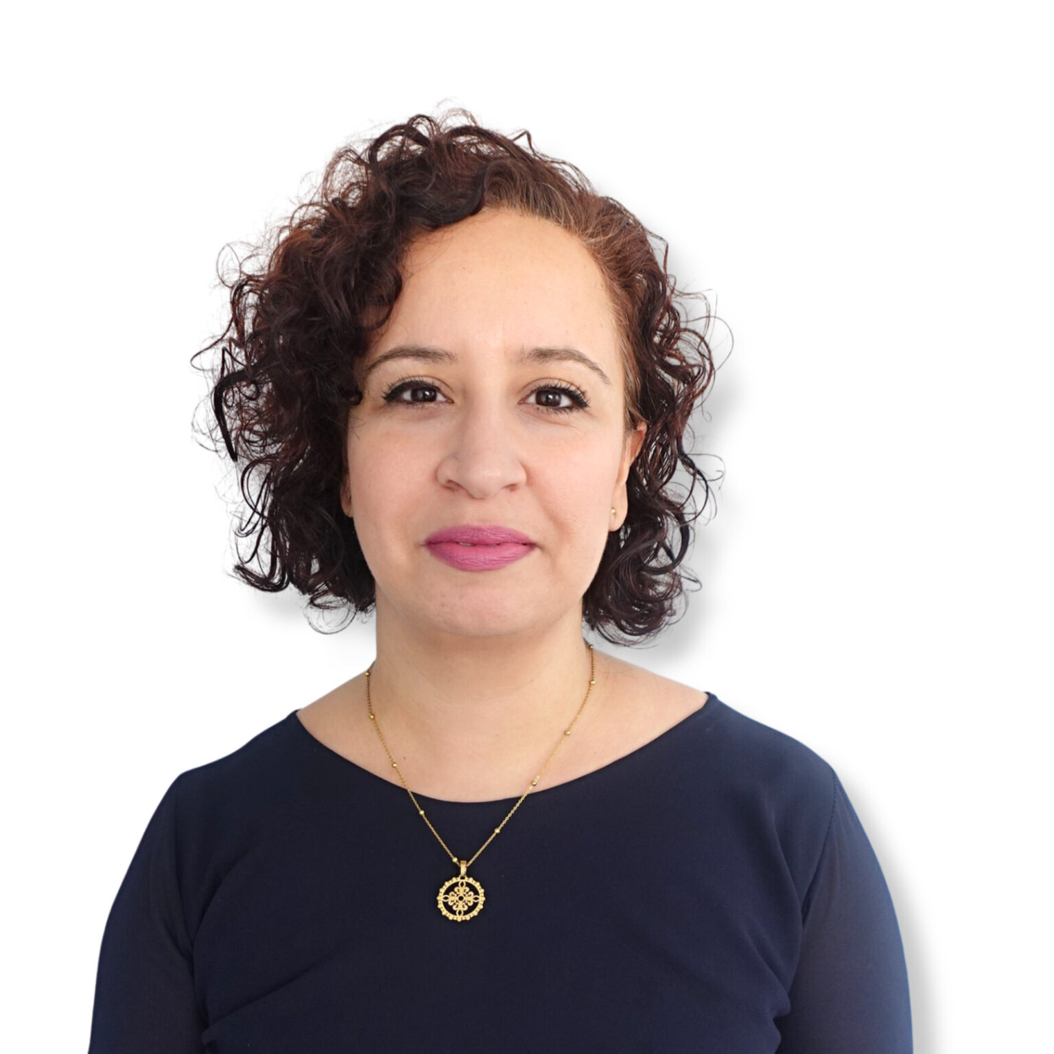 Calm woman with curly auburn hair and light makeup, wearing a navy top and gold necklace, expressing serenity and confidence in a mental health or psychological context.