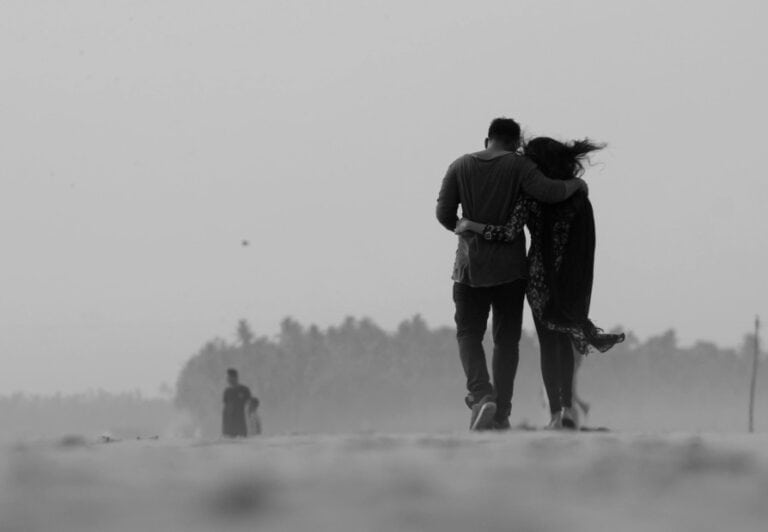 Comforting couple walking together along a peaceful beach, symbolising emotional support and intimacy in mental health.