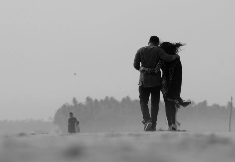 Comforting couple walking together along a peaceful beach, symbolising emotional support and intimacy in mental health.