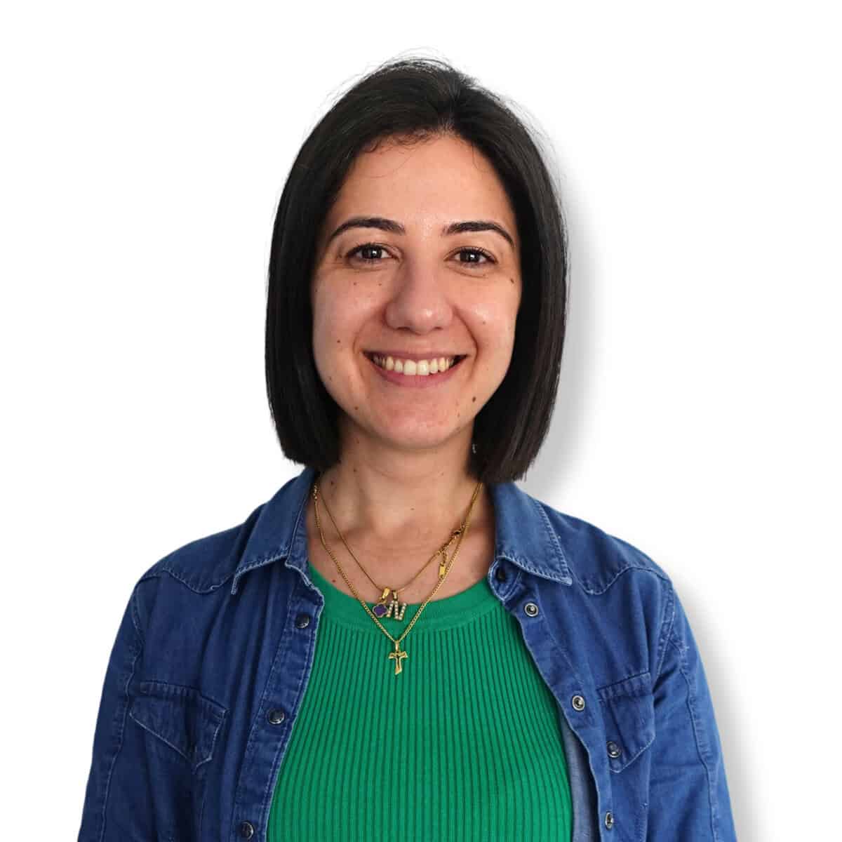 Calm woman therapist smiling, wearing casual denim jacket and green top, reflecting mental health support and emotional well-being.