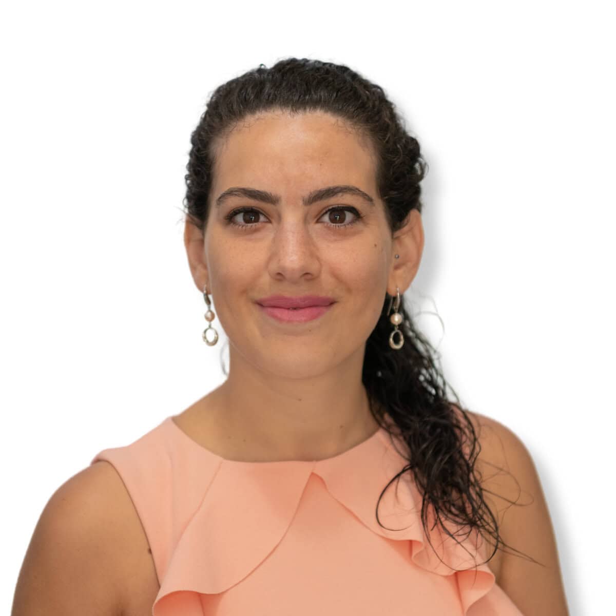 Calm and confident woman with curly dark hair and earrings, wearing a peach sleeveless top, representing mental health, self-care, and emotional well-being.
