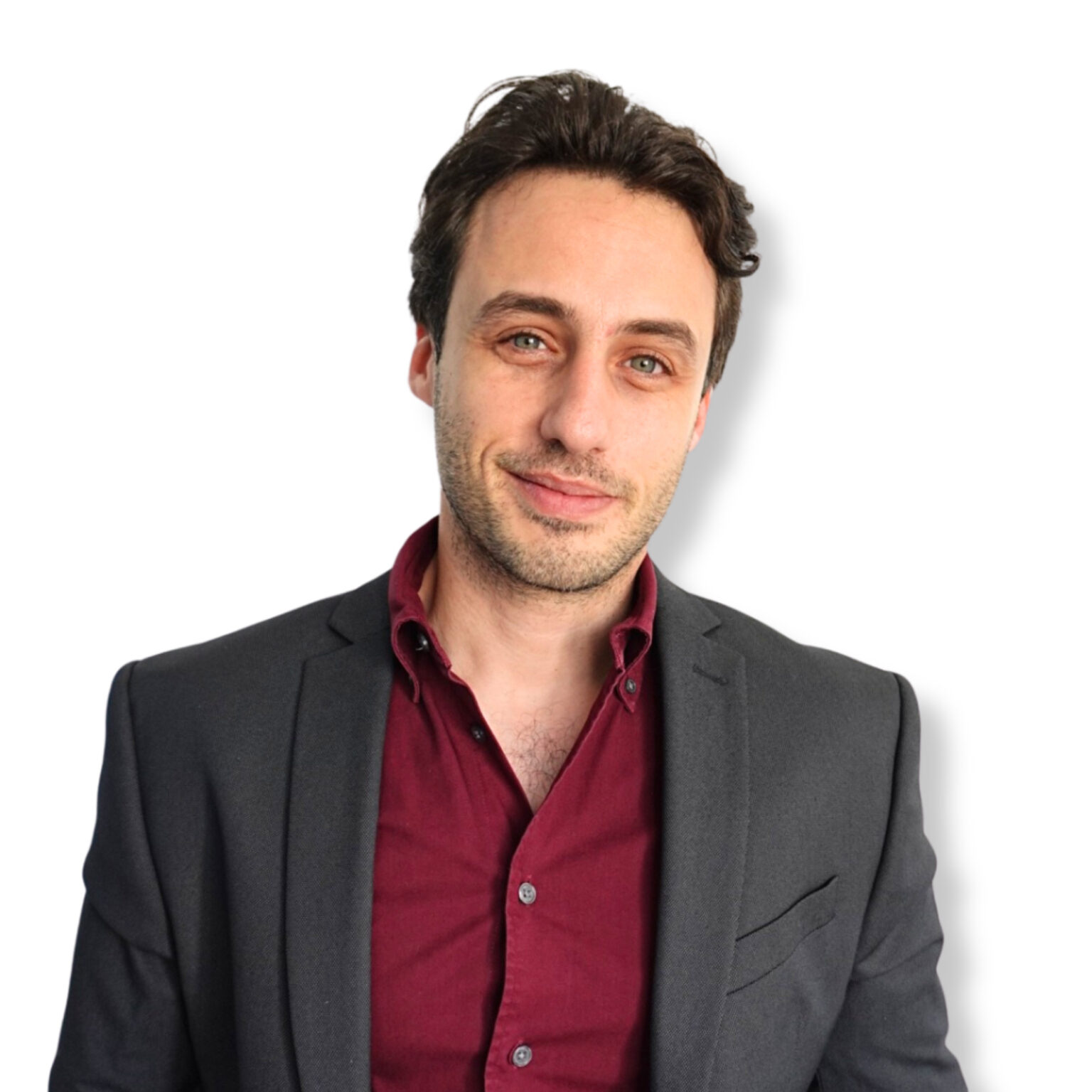 - A professional man in a dark blazer and burgundy shirt posing confidently against a plain white background.