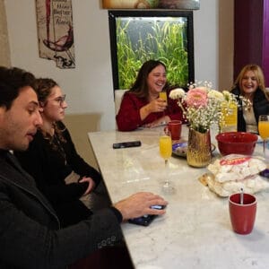 Relaxed social gathering of friends enjoying conversation and laughter in a warm indoor setting.