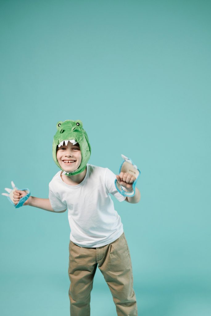 A young boy is seen dressing up as a crocodile, possibly cause it's his favorite animal. This alone is just one of the many benefits that come with Storytelling and Drama Activities with children.