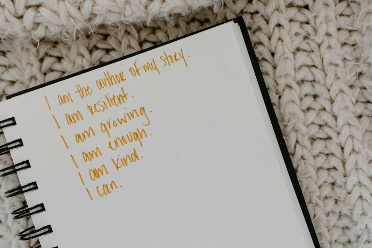 An open notebook is shown with multiple sentences decreasing in length as you go down. Looking closely, you'll spot the word "resilient" in the second sentence from top to bottom. All the sentences are ways of showing that small habits can strengthen resilience.