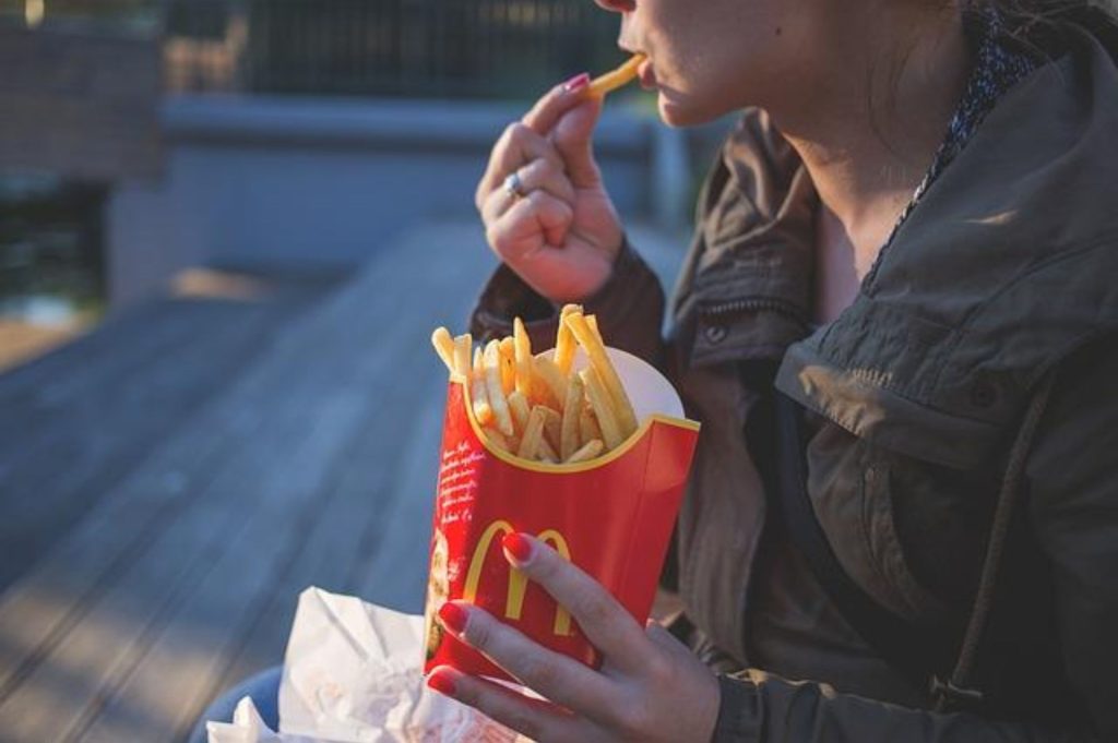 A person is seen sitting on a bench, enjoying the McDonald's fries he just bought for lunch. So basically, he's eating his problems away.