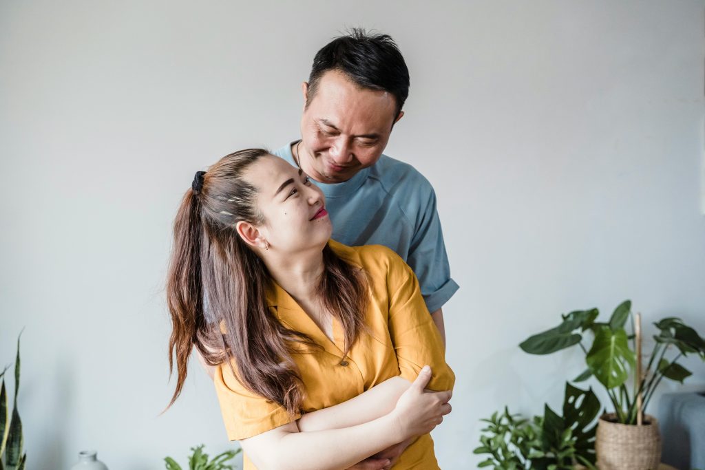 A woman is shown smiling at her husband, who's smiling back at her. They are (at least right now) on good terms with each other, as they are aware that their relationship will influence their kids according to the dynamics in question.