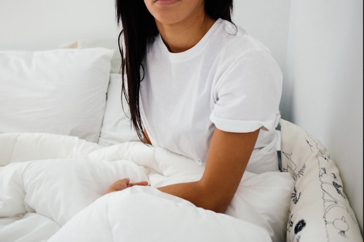 A woman can be seen in bed, wondering about what's possibly causing her to feel little to no sexual desire. There are Psychological And Physiological Factors At Play here.