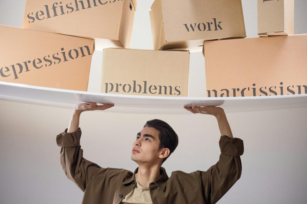 A man is shown carrying a lot of boxes, each with a different word on it. People mostly assume that Narcissism and Confidence are the same thing, when they're two separate terms in real life.