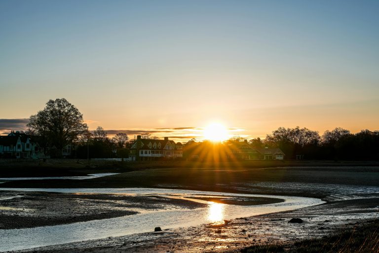 Sunrise over homes by the water, symbolising how sunshine boosts mood and energy naturally.