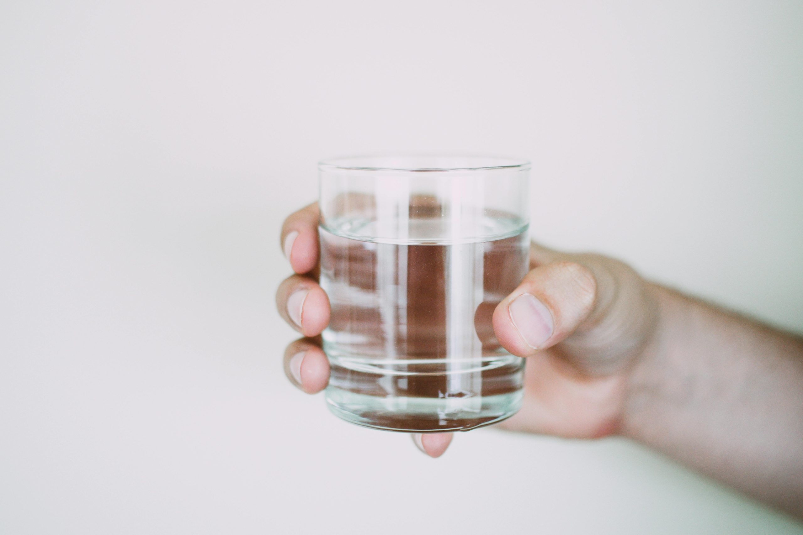 Hand holding a glass of water, highlighting the link between hydration and mental health benefits.