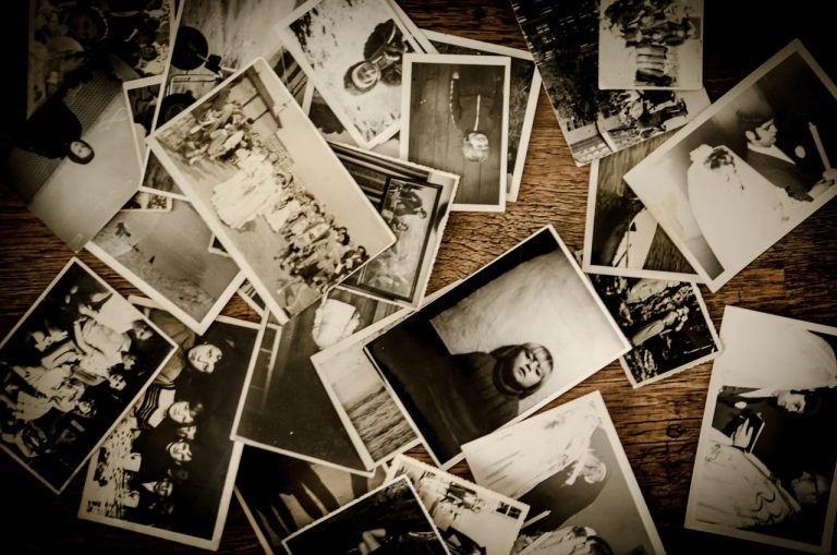 Scattered old childhood photos representing early memories that shape adult intimacy and relationships.