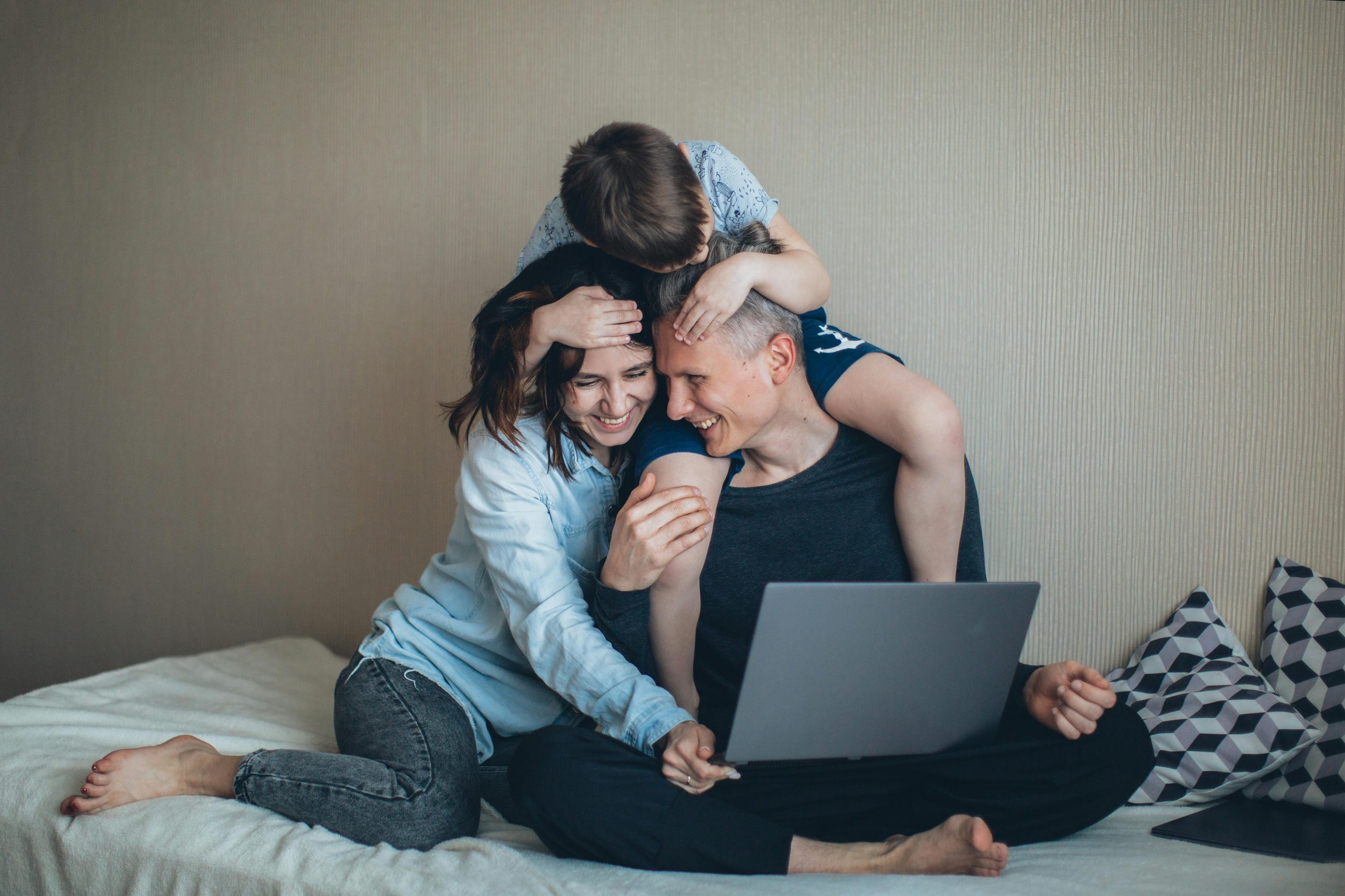 Happy parents juggling work and family time with their child during school holidays at home.