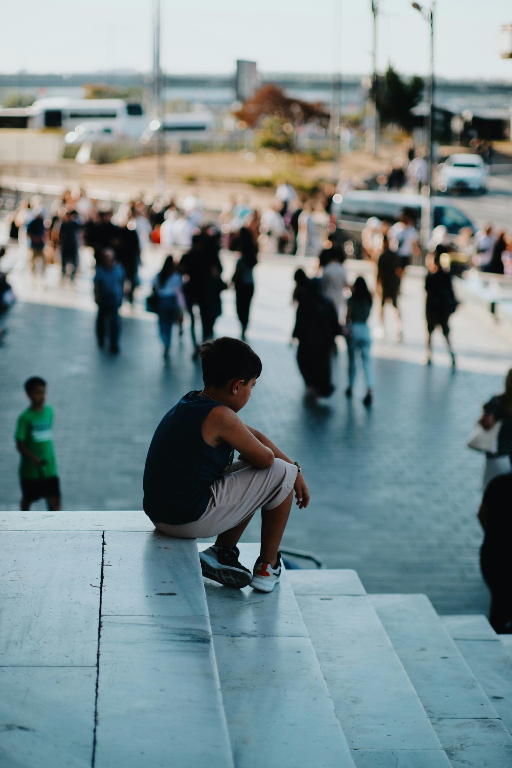 Boy sitting alone on steps in a crowd, symbolising building meaningful relationships.
