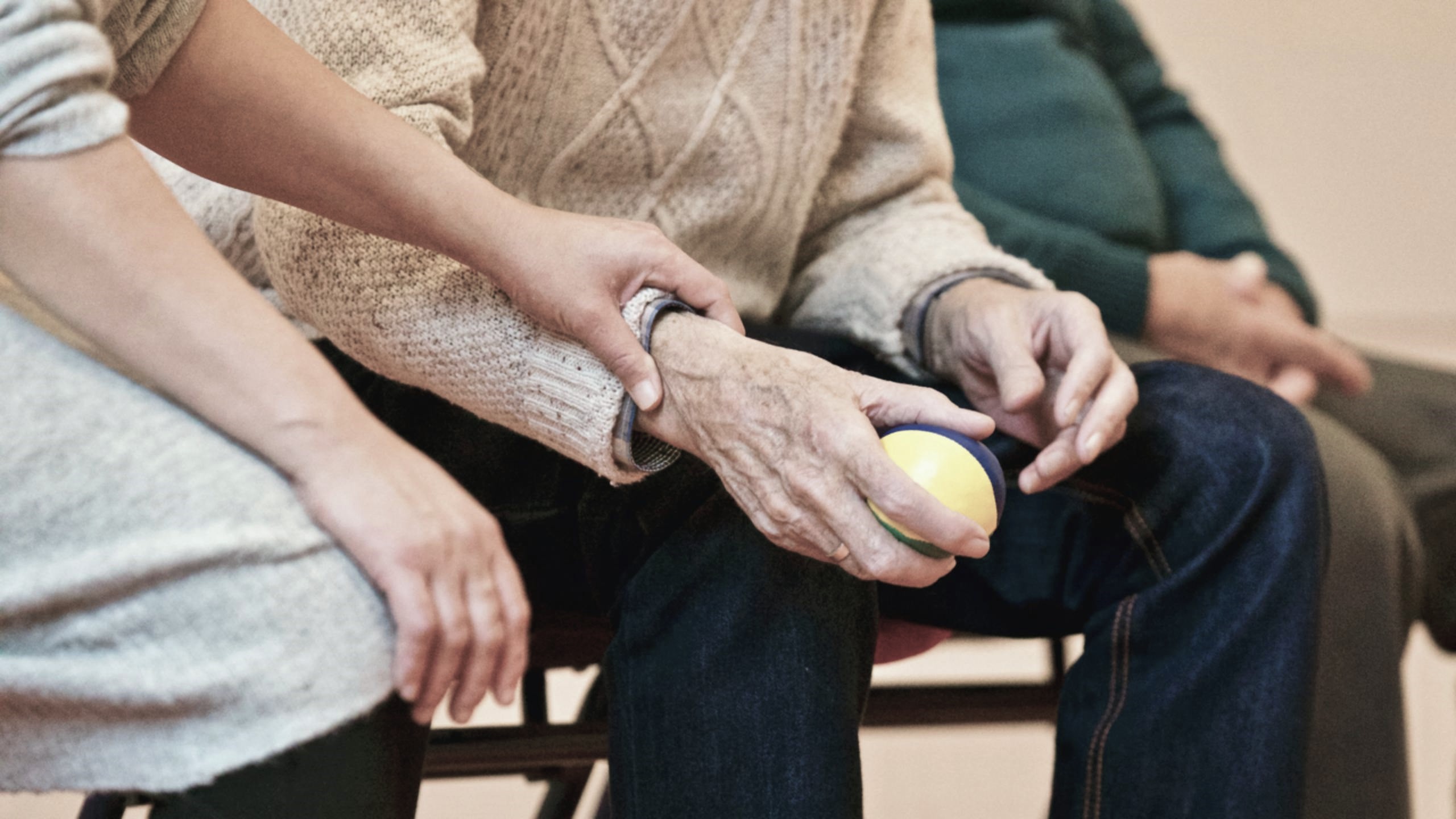 An older adult being gently supported in a group activity, reflecting social connection and Purpose.