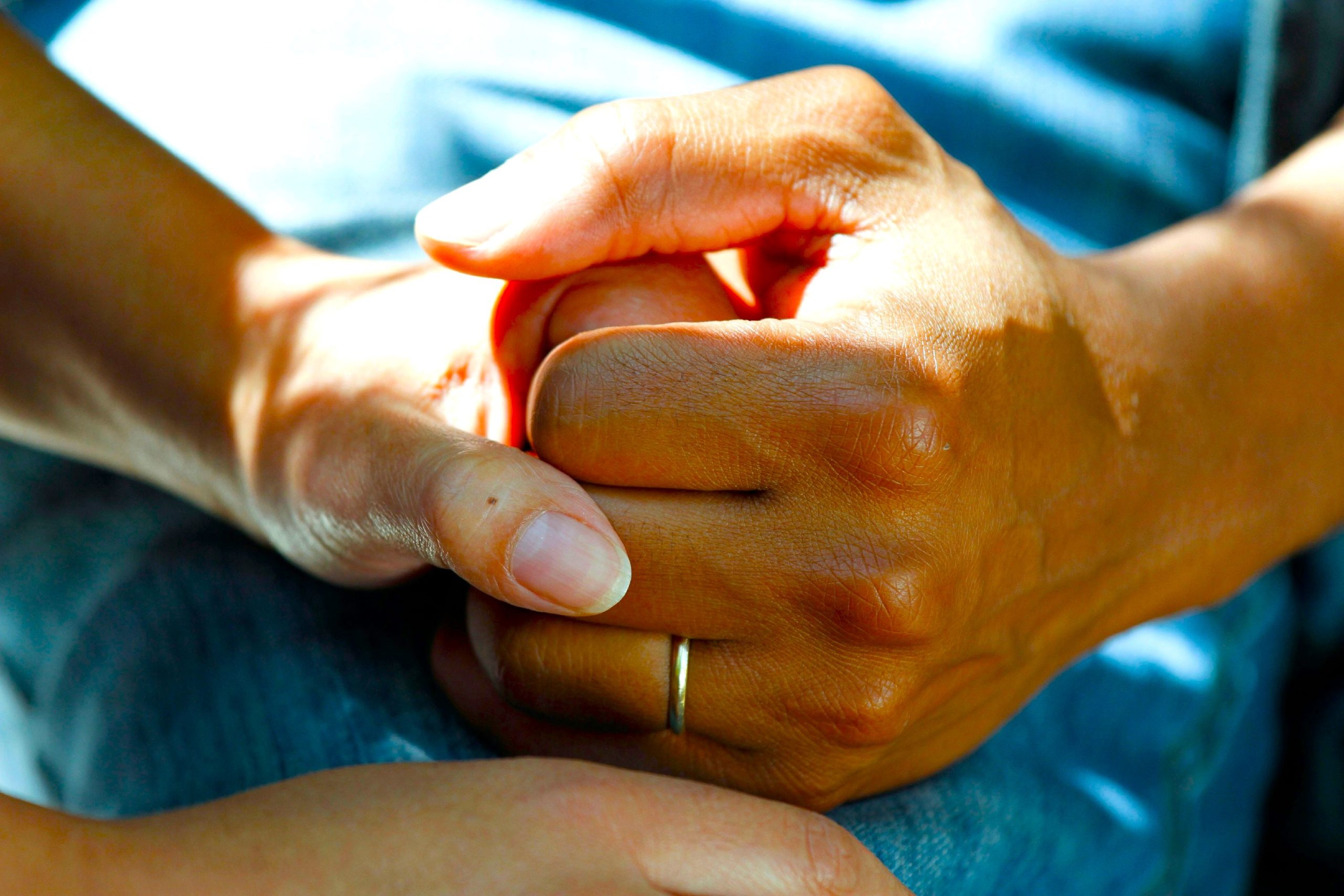 Two people holding hands calmly, symbolising family support and care using meaningful Verbal Cues.