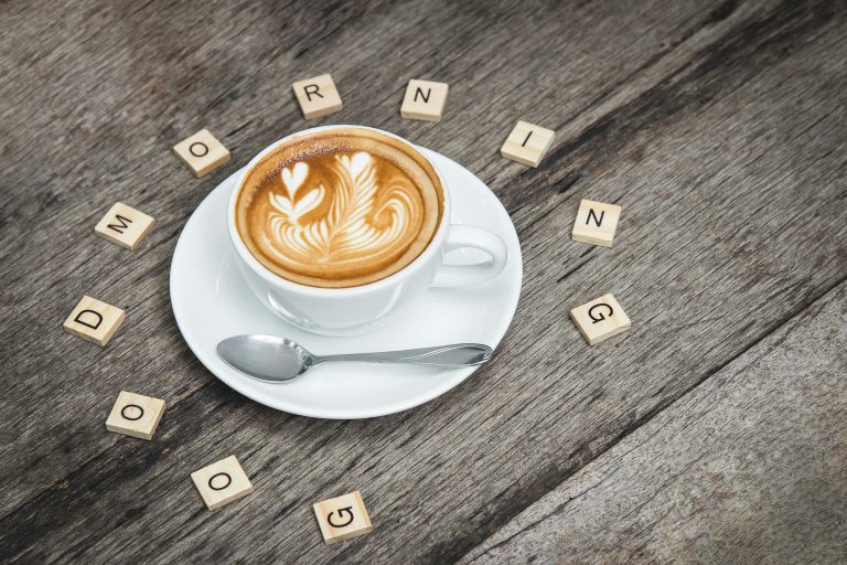 Latte with heart design on wooden table, spelling “Good Morning,” representing warmth, care, and Breakfast at Willingness.