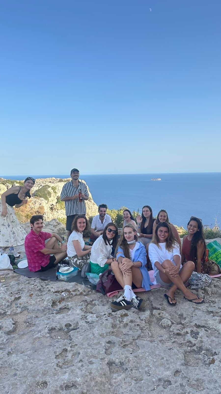 Relaxed group of friends enjoying a seaside outdoor gathering, promoting social connection and well-being.