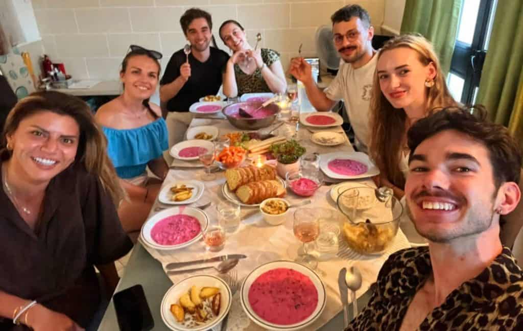 Kosher dinner with a diverse group of friends, sharing a lively and joyful moment around a table filled with colourful dishes and desserts, highlighting social connection and cultural celebration.