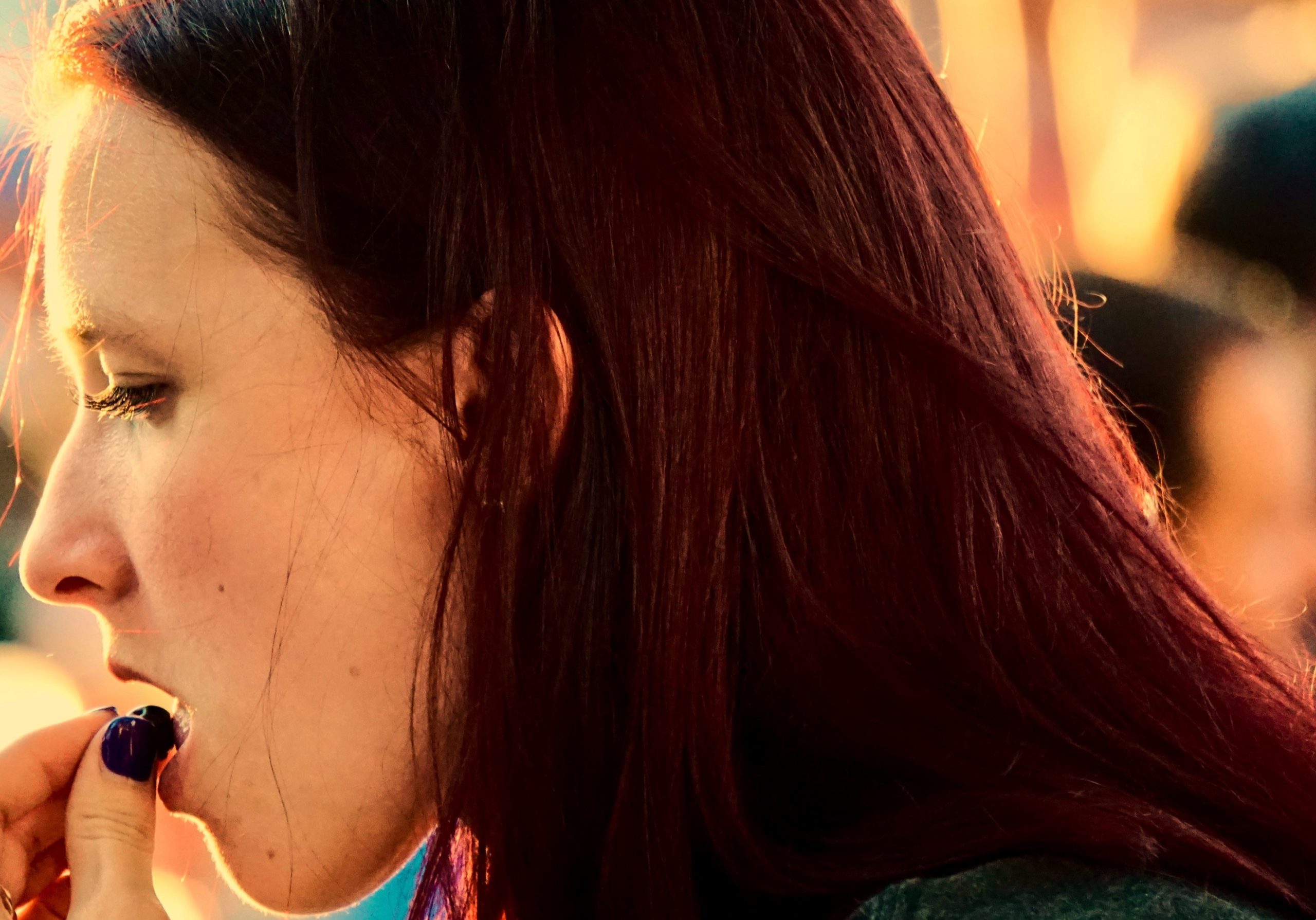 Young woman placing a pill in her mouth at a crowded event, illustrating the risks of Peer Pressure Drugs.