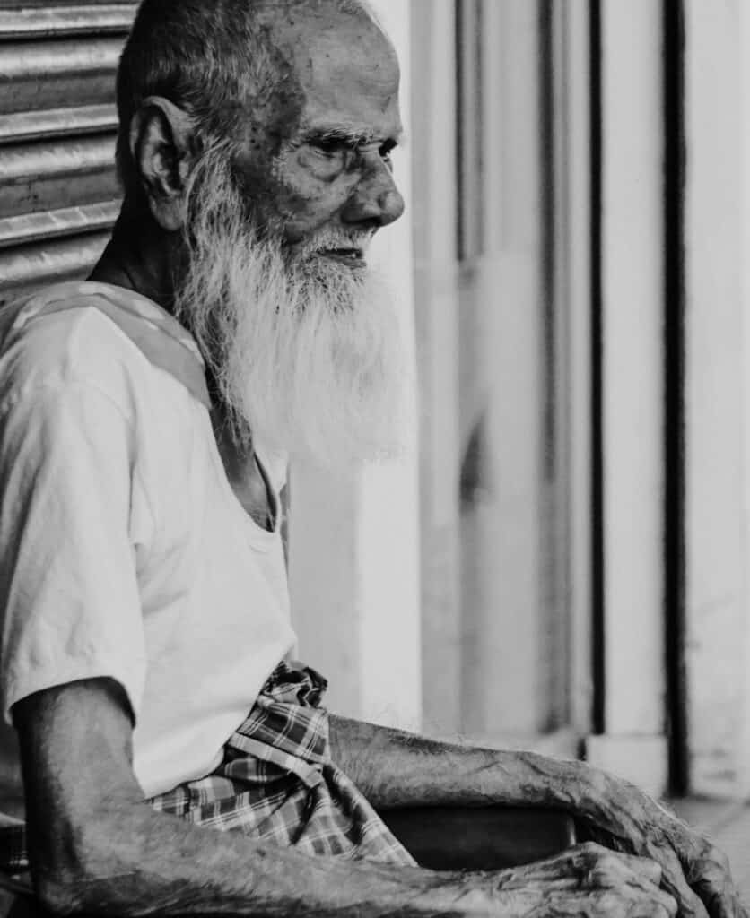 Elderly man sitting thoughtfully, symbolising resilience and challenges of cancer in later life through Life Experience.