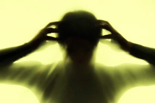 Blurred figure holding head, symbolising stress and trauma responses linked to Hypervigilance After Traumatic Experiences.