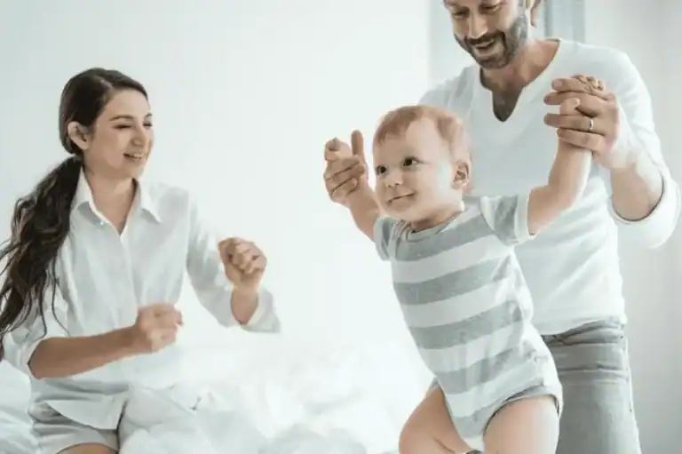 Encouraging father and happy mother supporting their smiling toddler, fostering a positive family environment and emotional development.