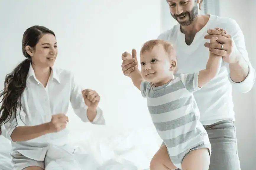 Encouraging father and happy mother supporting their smiling toddler, fostering a positive family environment and emotional development.