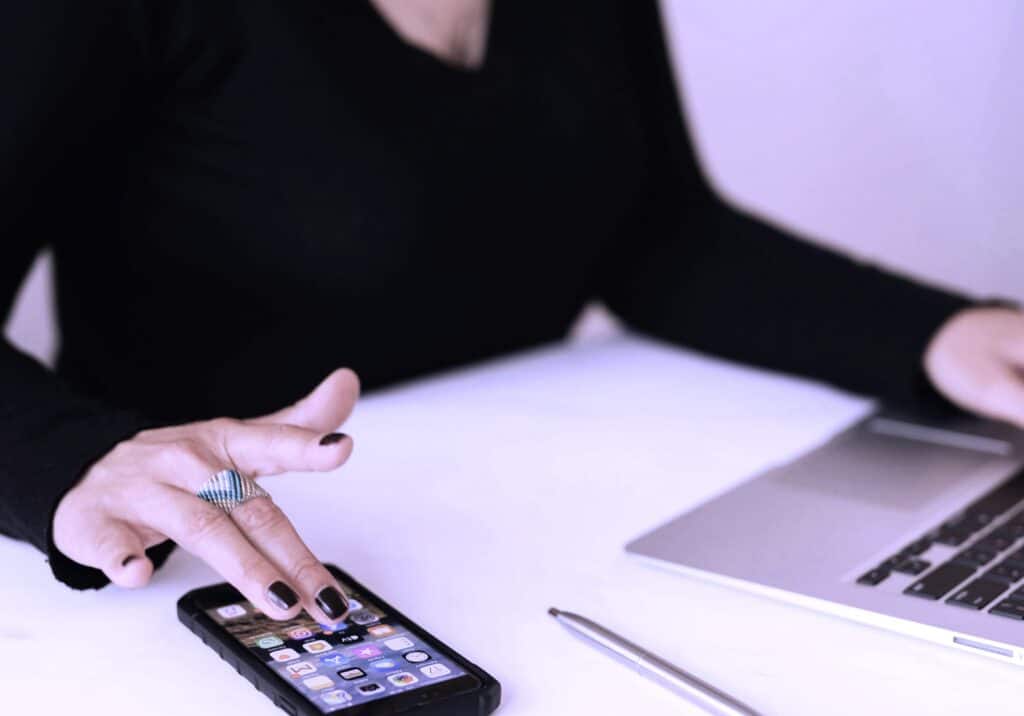 Freelancer working on a mental health project using a smartphone and laptop, symbolising the integration of digital tools in modern mental health support and therapy.