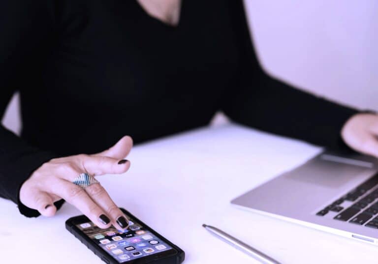 Freelancer working on a mental health project using a smartphone and laptop, symbolising the integration of digital tools in modern mental health support and therapy.