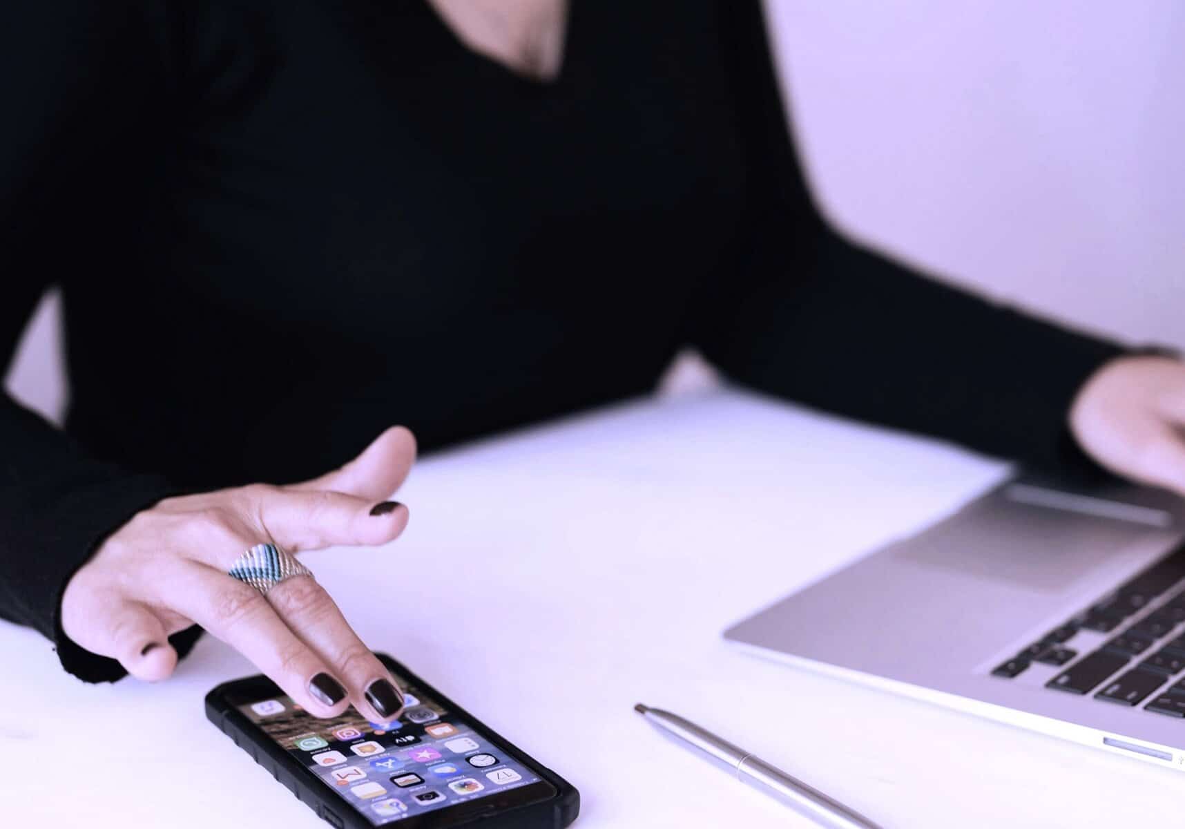 Freelancer working on a mental health project using a smartphone and laptop, symbolising the integration of digital tools in modern mental health support and therapy.