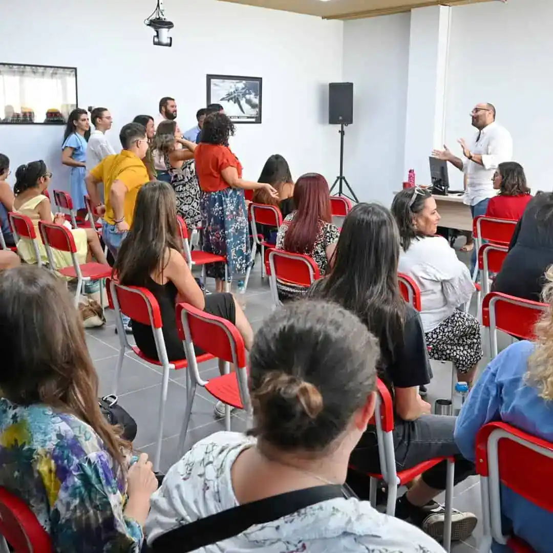 People attending a mental health seminar listening to a speaker in a modern, well-lit classroom setting. The image depicts a supportive environment focused on mental health awareness and education.